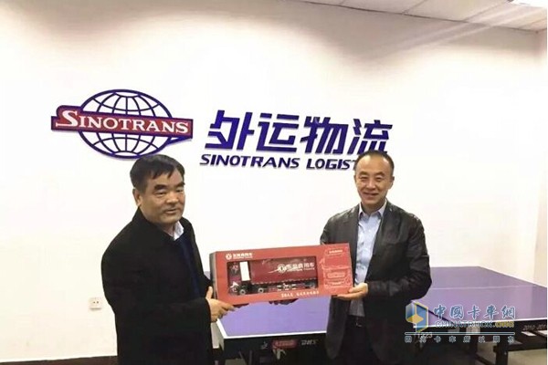 東風商用車有限公司副總經理孫振義向中國外運物流發展有限公司總經理李軍贈送東風天龍車模